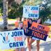 OARS crew hold signs welcoming guests to the open boathouse event