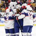 Team USA celebrates in their white jerseys after scoring a goal.