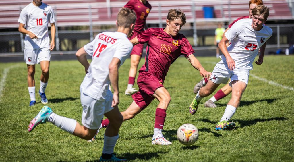 Image of Minneapolis Roosevelt High School Boys varsity soccer defender as he takes the ball forward , weaving througha group of opponents during a game at Al Gowan’s stadium.