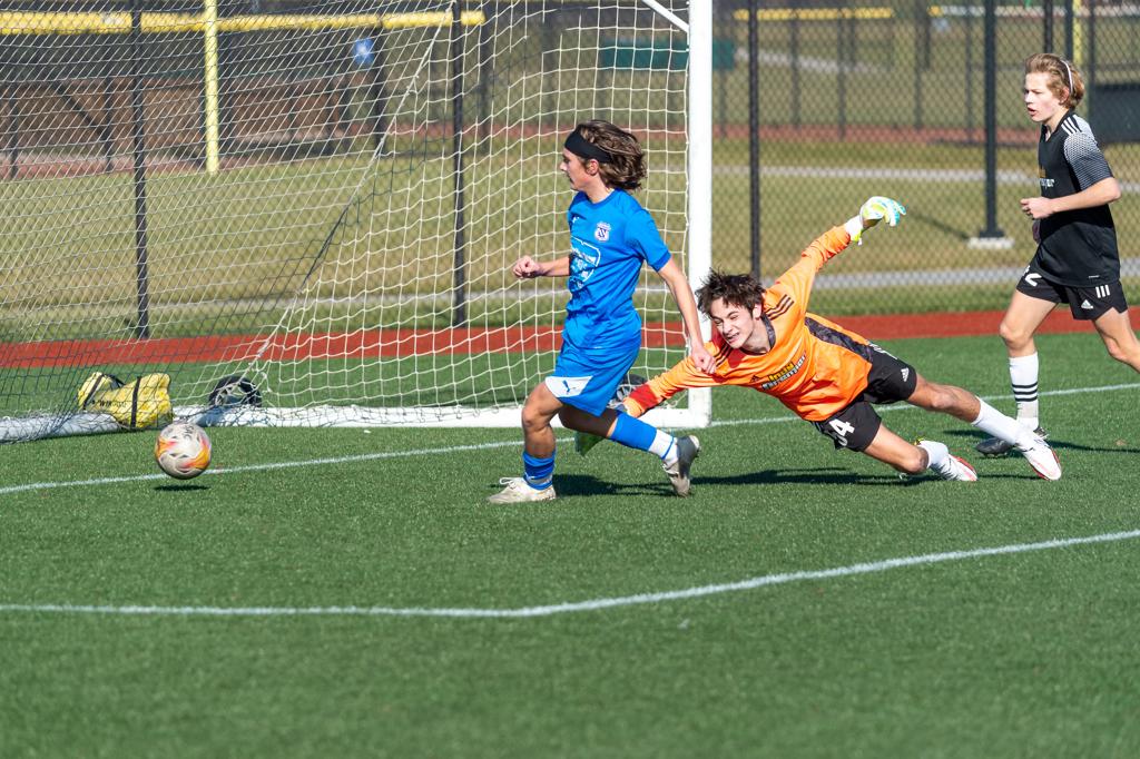 Soccer player watching ball roll into the net