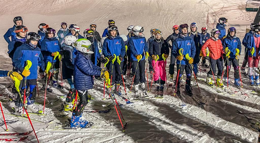 Image of the Minneapolis Alpine Ski Team gathered at the base of slope by the chair lift during a practice